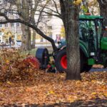 a-tractor-with-a-blower-cleans-a-city-park-lawn-an-RCHRVBQ.jpg